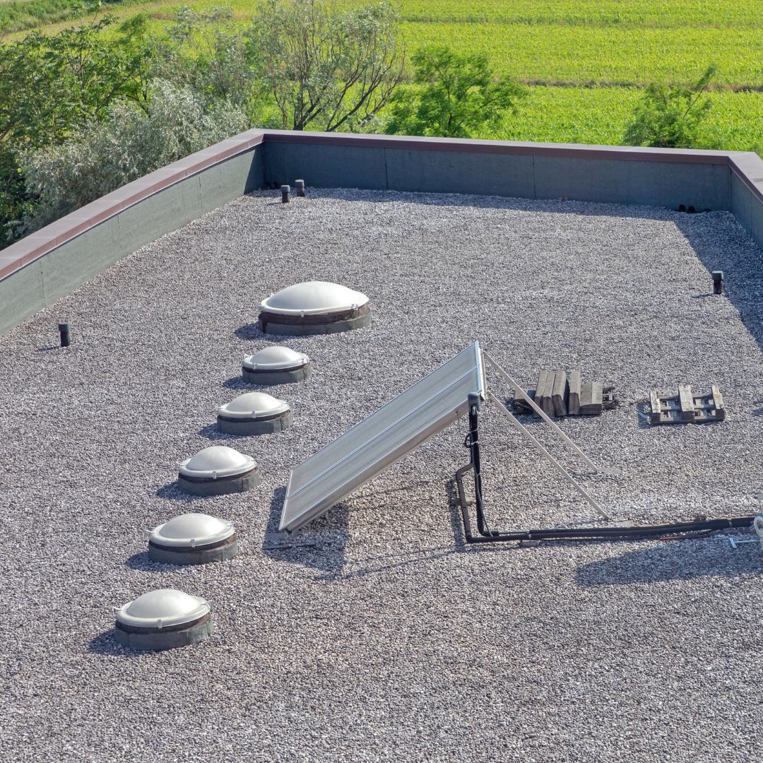 Skylight domes in a row across a gravel-ballasted C & H roof, fields beyond